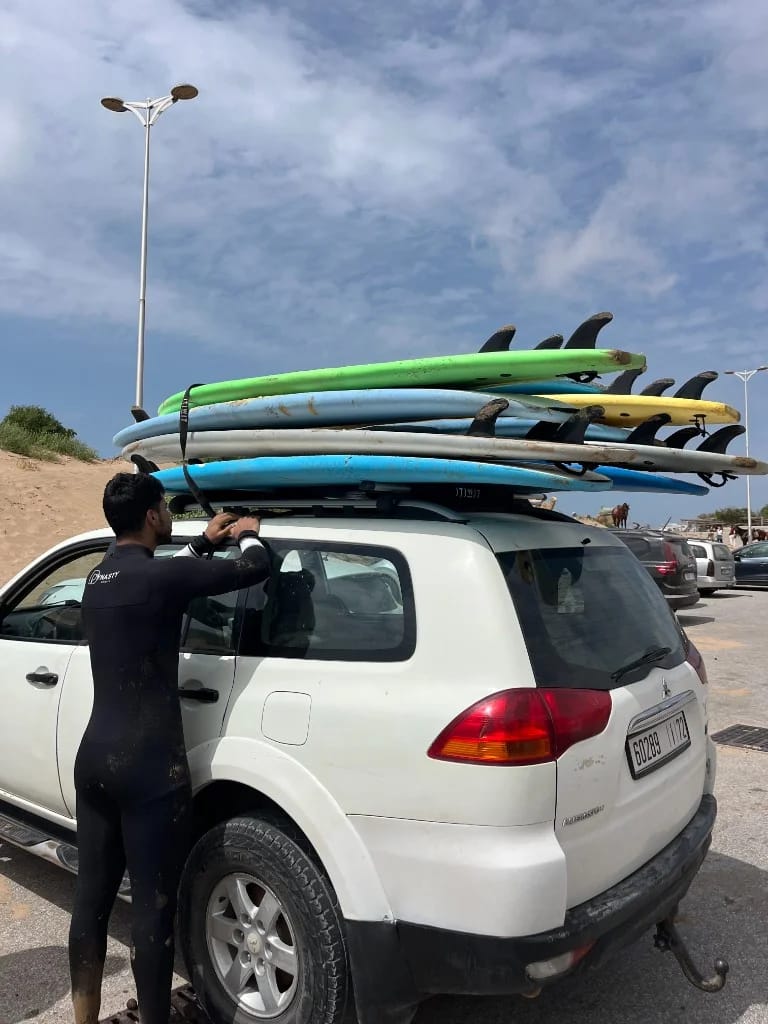 Guest securing surfboards on a 4x4 roof rack before a Morocco surf trip from Essaouira