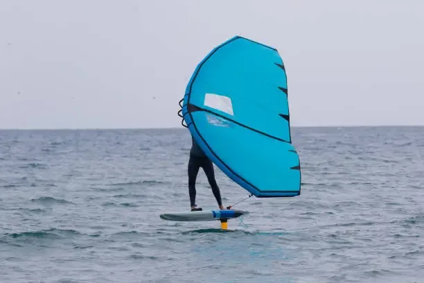 Wing foiling lesson on Essaouira bay with cyan wing and hydrofoil